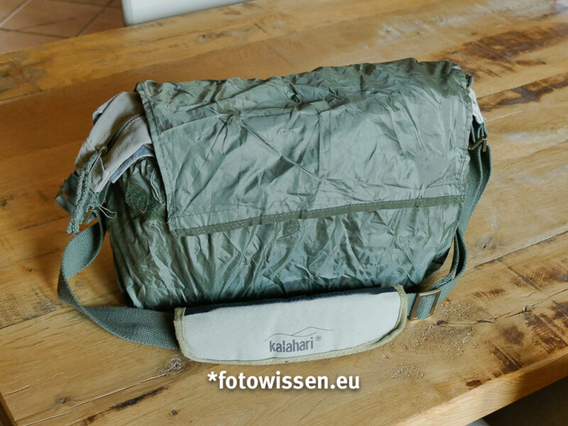 Der Regenüberzug ist in der hinteren Tasche mit Reißverschluss untergebracht. Er wird von unten nach oben über die Tasche gestülpt. Das ist ganz einfach...