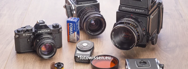 Drei analoge Kameras (Pentax Kleinbild, Hasselblad Mittelformat 6x6, Mamiya 6x7), ein Belichtungsmesser, Filmrollen und Objektivfilter für die analoge Fotografie.